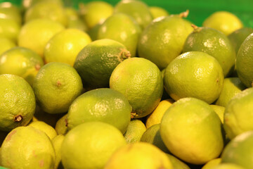 Limes close-up with selective focus. Heaps of tasty limes for sale in a store. Variety of fresh produce. Ripe limes for sale in a supermarket. Ripe, juicy, green fruits with vitamin C.