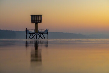 sunrise over the lake with the reflection of the sports booth. colorful sunrise over the retention reservoir.