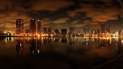 A serene nighttime city skyline reflects on a tranquil lake, framed by a sandy beach, creating a picturesque urban landscape.