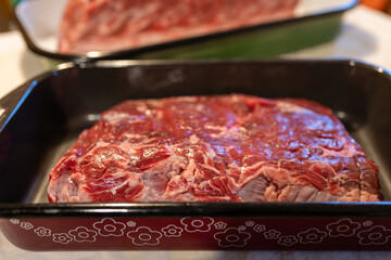 A close-up of fresh raw beef cuts placed in baking trays, highlighting the rich marbling and texture of the meat. 