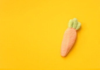 Soft-textured marshmallow carrot with green leaves on a bright yellow background. Ideal for festive decor, cards, and branding.