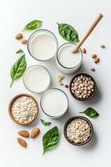 A variety of plant-based milk options, including almond, oat, and soy milk, arranged with grains, nuts, and green leaves on a white background. A healthy and natural dairy-free concept.

