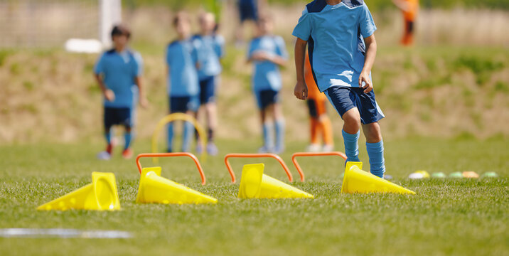 Football training camp for school kids. Children playing soccer training games outdoors. Kids running at obstacle course