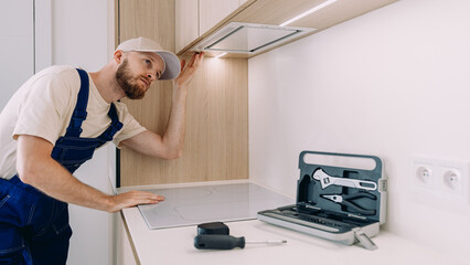 Professional handyman performs kitchen cabinet installation and adjustment
