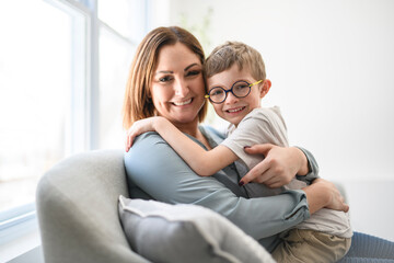Portrait of boy smiling at camera with her mother at home