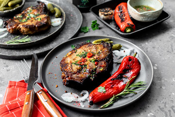 Delicious dinner for two. Pork steak on a plate. Dark background.
