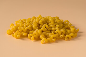 Side view of a raw italian durum wheat cavatappi pasta against a light ochre background . Isolated...