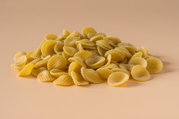 Side view of isolated a raw Italian durum wheat orecchiette pasta on a light ochre background .