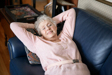 Beautiful senior woman in the living room lay on sofa