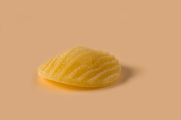 Orecchiette pasta isolated on light ochre background , side view . Macro shot of one isolated raw...