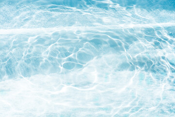 Bluewater waves on the surface ripples blurred. Defocus blurred transparent blue colored clear calm water surface texture with splash and bubbles. Water waves with shining pattern texture background.