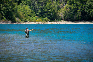 Man fishing in lake, los alerces national park, argentina,