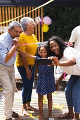 woman taking selfie with happy diverse family at in garden celebration