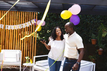 diverse couple celebrating birthday in garden with balloons and decorations