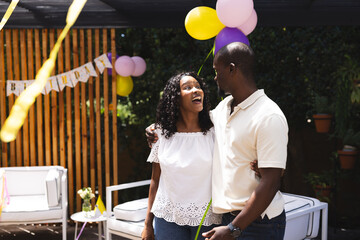 diverse couple embracing with joyful expressions celebrating birthday in garden