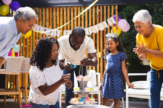 diverse family decorating cupcakes in garden, celebrating birthday together
