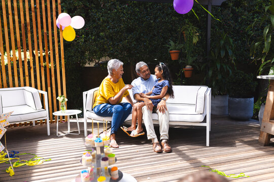 Sitting with granddaughter on patio, grandparents sharing diverse family time and conversation