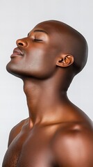 Serene portrait of a young Black man with a shaved head, his eyes closed in peaceful contemplation against a neutral background.