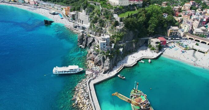 Stunning aerial panorama of Monterosso al Mare in Cinque Terre, Italy with anchored tourist boat and hill tower