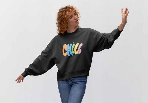 A redhead woman wearing a cozy jumper strikes a fashionable pose in front of a neutral background. PSD ready to customize with your design