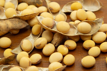 V&aacute;rios gr&atilde;os e vargens de soja espalhados sobre uma mesa de madeira.