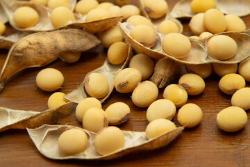 Vários grãos e vargens de soja espalhados sobre uma mesa de madeira.