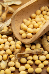 Detalhe de uma concha de madeira cheia com grãos de soja sobre a mesa com muitos grãos espalhados.