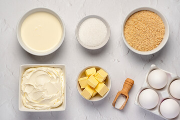 Food photography of raw ingredients of New York cheesecake, cream, soft cheese, sugar, butter, shortbread crumbs, vanilla