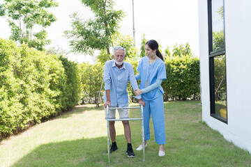 Fototapeta premium Nurse taking care and healthcare support in consultation at home. Asian woman caregiver taking care senior man walking with walker at garden. People and health care concept