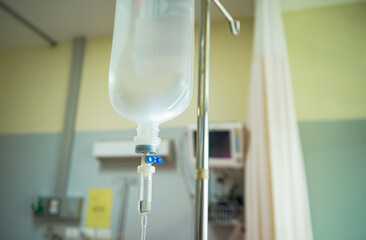 Close up of saline solution bottle for patient with emergency room in hospital background. Intravenous fluid infusion set for nursing room patients Medical and health concepts