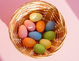 Basket with colorful Easter eggs on a pink background, top view. The concept of the Easter holiday.
