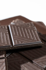 Dark chocolate pieces on white background, macro texture