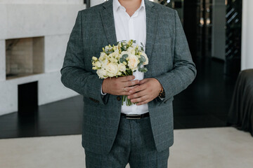 Close-up photo of a man's hands holding a watch and adjusting the collar of his jacket and shirt. Businessman in a gray jacket