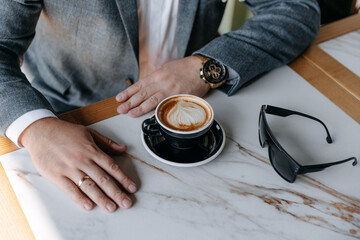 Close-up photo of a man's hands holding a watch and adjusting the collar of his jacket and shirt. Businessman in a gray jacket