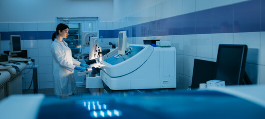 A young woman works in a modern laboratory with advanced equipment and an analyzer. The concept innovative technologies and top-notch equipment for precise scientific research.