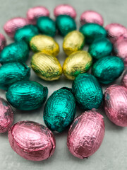 Chocolate easter eggs wrapped in pink, gold, and teal foil creating festive arrangement