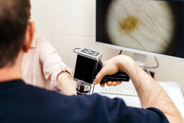 A dermatologist examines the skin of a young patient using advanced equipment, displaying cellular...