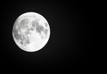 Obraz premium A very detailed full moon glowing brightly against a stark black night sky, showcasing the lunar surface's craters and textures. Its a close up, with