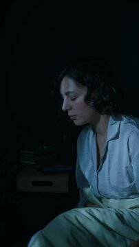 Vertical shot of young woman suffering from sleepwalking at night, walking around her bedroom in pajama at night