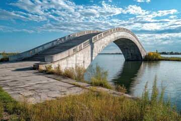 Beautiful arched bridge over calm water under a bright blue sky with scattered clouds