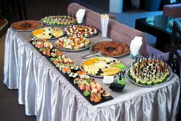 Snacks for the holiday, catering. Various snacks. Assortment of salads, sushi and buffet dishes. Meat, fish, cheese, salads, fruits and vegetables, sauces and canapes for celebrating a festive event.