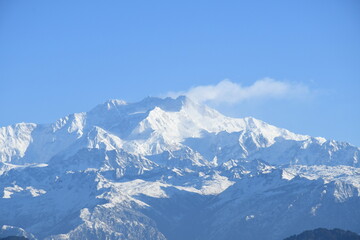 Naklejka premium A breathtaking view of a snow-covered mountain range with a clear blue sky in the background. The pristine white peaks and rugged terrain create a stunning natural landscape,