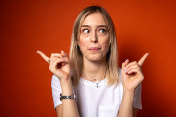 Portrait of a funny young, emotional girl making a fish face, lips and pointing with both hands....