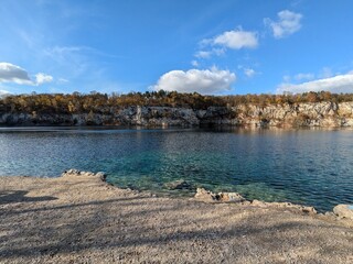 Crystal Clear Lake Surrounded by Rocky Cliffs and Autumn Trees