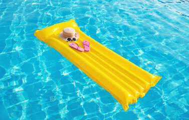 Beach summer holiday background. Inflatable air mattress, flip flops and hat on swimming pool.