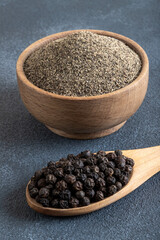Ground black pepper with grains of black pepper on dark background 