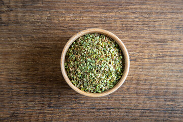 A bowl full of dried and ground organic mountain thyme on wooden table
