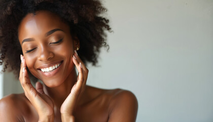 Smiling radiant beautiful black woman touches face with hands against light background. Clean skin, perfect smile, wellness concept. Beauty spa salon advertising banner or poster, copy space.