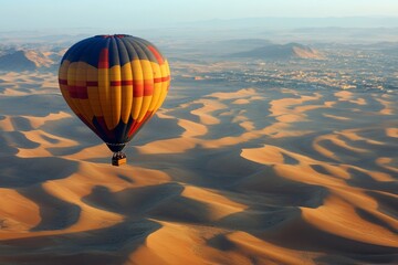 Obraz premium Colorful hot air balloon over desert dunes at sunrise with vast landscapes