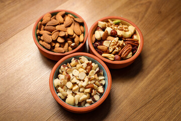 Walnut, macadamia nut, cashew nut, pecan on the plate and isolated on brown background. Pile of mixed nuts.